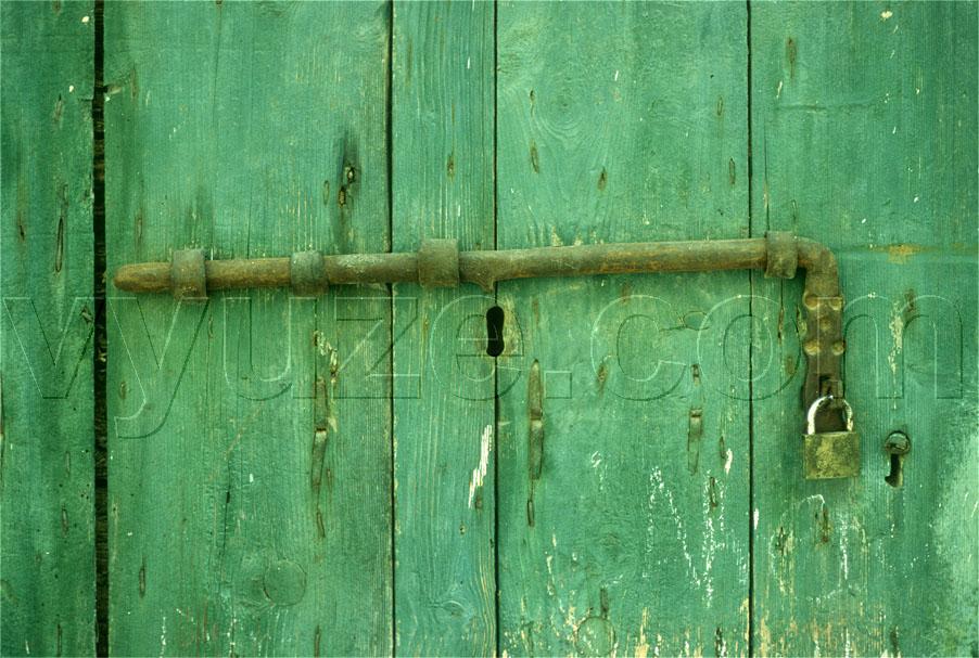 Green painted door with bolt and lock / Location: Greece